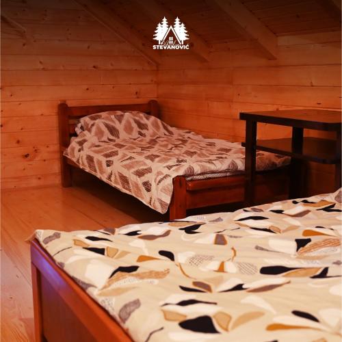 a bedroom with two beds in a log cabin at Vikendica Stevanovic in Doboj