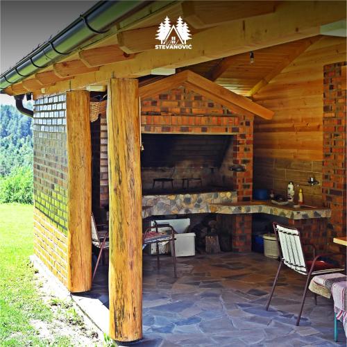 una cabaña de madera con patio y chimenea en Vikendica Stevanovic, en Doboj