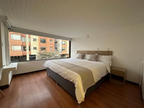 a bedroom with a large bed and a large window at One Fourteen Rooms in Bogotá