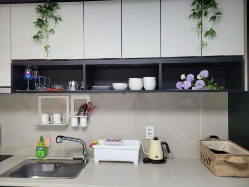 a kitchen counter with a sink and white cabinets at DAON STAR BnB j6 in Daegu
