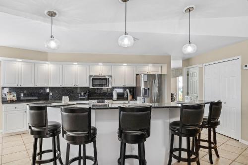 a kitchen with white cabinets and black bar stools at Gulf Access, Heated Pool, Bikes, Kayaks - Comfort on the H2O - Cape Coral - Roelens Vacations in Cape Coral