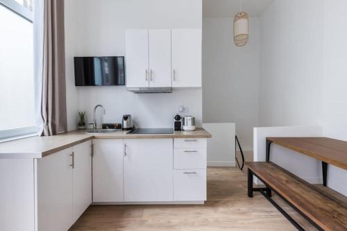 une cuisine avec des armoires blanches et une table en bois dans l'établissement Sentier Réaumur - Beautiful Apartment III, à Paris