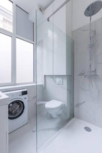 La salle de bains blanche est pourvue de toilettes et d'un lave-linge. dans l'établissement Sentier Réaumur - Beautiful Apartment III, à Paris