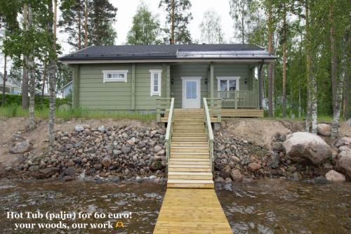a small green house with a wooden walkway leading to it at SResort Saunas - hot tub, palju in Imatra