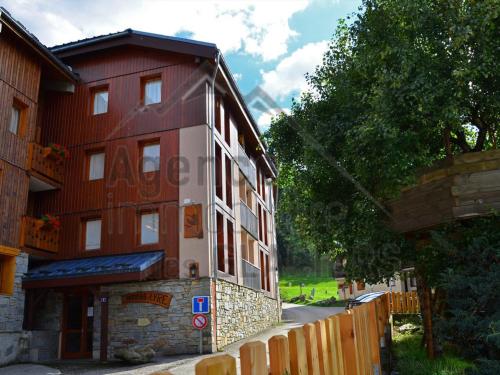 un bâtiment rouge et blanc à côté d'une clôture en bois dans l'établissement Appartement Charmant pour 5 Pers. à Montchavin, 2 Balcons, Proche Pistes, Parking Gratuit - FR-1-329-81, à La Plagne Tarentaise