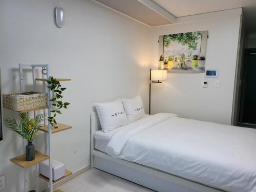 Schlafzimmer mit einem Bett mit weißer Bettwäsche und Kissen in der Unterkunft DAON STAR BnB j6 in Daegu