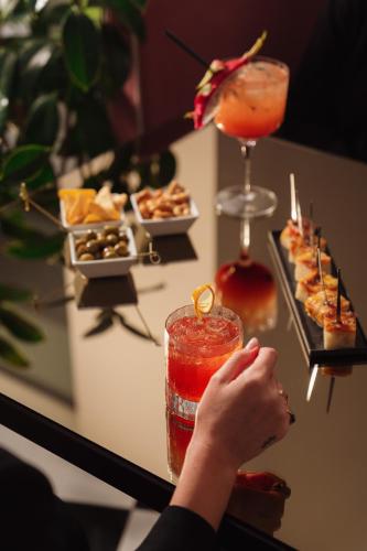 a person holding a drink next to a table with food at Hotel Morfeo in Milan