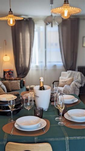 a table with plates and glasses and a bottle of wine at LE CEMAROSE Cottage & Spa Terrace Garden & lovely View in Épernay