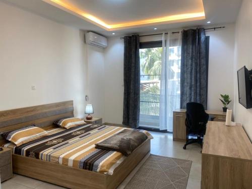 Un dormitorio con una cama y un escritorio y una ventana. en CHEZ CODOU FANN - POINT E, en Dakar