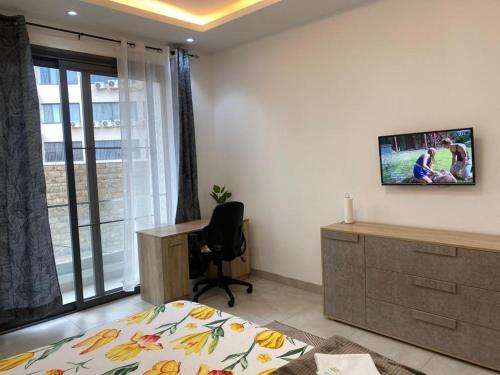 a bedroom with a bed and a desk and a window at CHEZ CODOU FANN - POINT E in Dakar