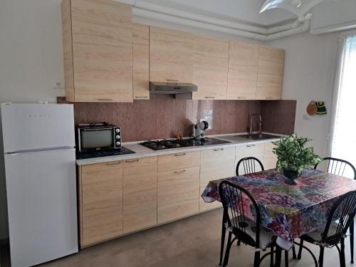 a kitchen with a table and a white refrigerator at Appartamento Torre Pedrera Rimini in Rimini