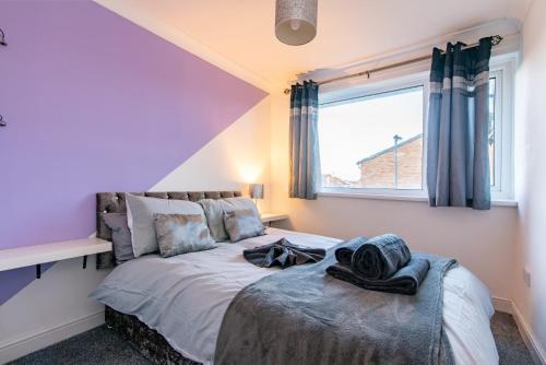 a bedroom with a bed with purple walls and a window at Bodmin House - Charming 3-Bedroom Terrace House with Private Enclosed Garden in Wallsend