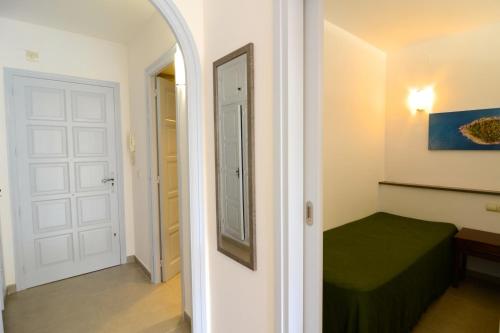 um corredor com um quarto com uma cama e um espelho em Jardins del Mar 48 em L'Estartit