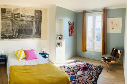 een slaapkamer met een bed, een stoel en een raam bij The artist's apartment near the metro in Saint-Denis