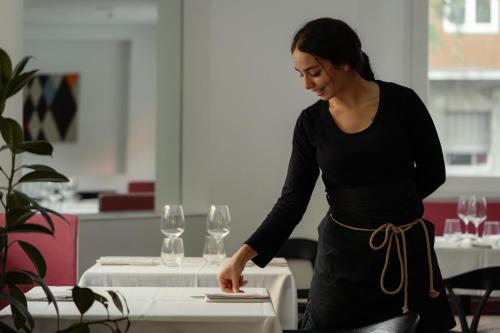 a woman standing next to a table with wine glasses at Hotel Morfeo in Milan