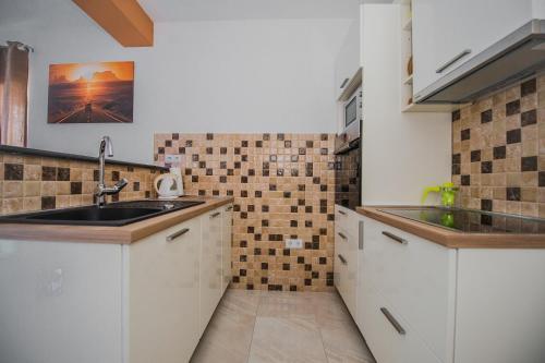 a kitchen with white cabinets and a sink at Apartments Villa Monique in Rogoznica