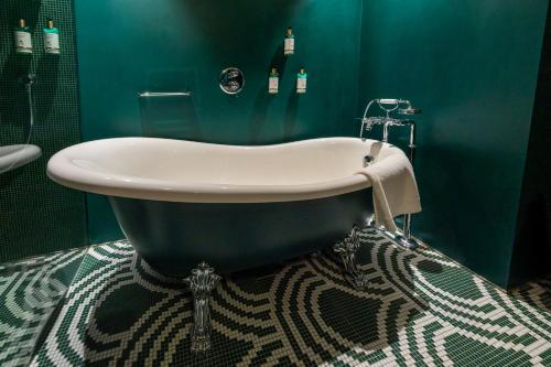 a bath tub in a bathroom with a green wall at Art Legacy Hotel Baixa-Chiado in Lisbon