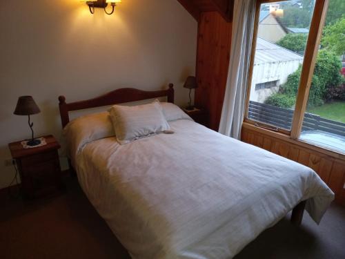 a bed in a bedroom with a large window at Complejo Paimun in San Martín de los Andes
