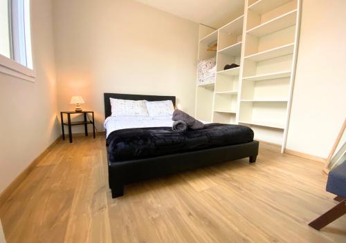 een slaapkamer met een bed met een zwarte poef bij Aux Pommiers - Poitiers CHU - CAMPUS - La Conciergerie in Poitiers