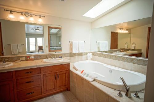 a bathroom with a sink, bathtub, and mirror at Sea & Sand Inn in Santa Cruz