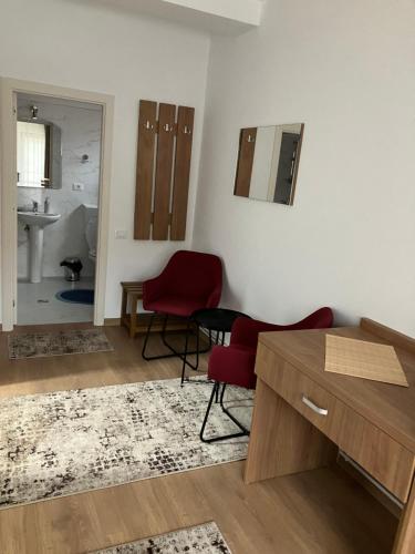 Căciulata的住宿－Casa BABI，客厅配有2把红色椅子和书桌