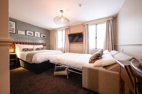 um quarto de hotel com duas camas e um sofá em The Bears Head by Innkeeper's Collection em Sandbach