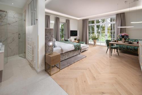 a bedroom with a bed and a desk and a bathroom at SCHLOSSRESIDENZ - Boutique Apartments & Hotel Suiten in Schloß Ricklingen