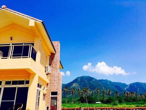 a yellow house with mountains in the background at Tamowan in Donghe