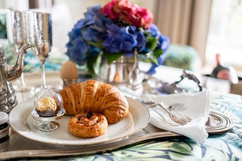 a plate with a croissant on a table with flowers at SCHLOSSRESIDENZ - Boutique Apartments & Hotel Suiten in Schloß Ricklingen