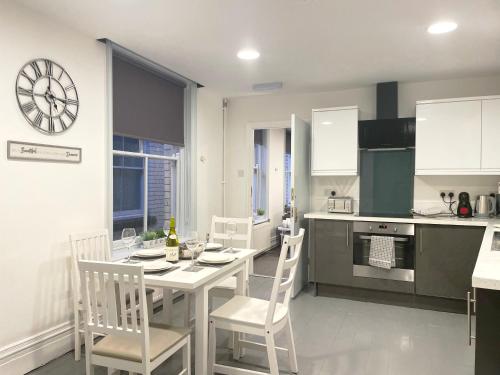 a kitchen with a table and chairs and a clock on the wall at Central penthouse by HNFC Stays in Newcastle upon Tyne