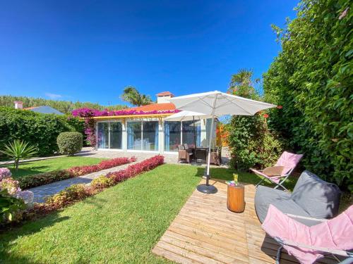 a patio with two chairs and an umbrella at Terra Vivaz - Ribeira Cottage in Ribeira Grande