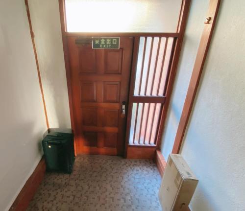 a hallway with a wooden door and a trash can at 民宿奈良山月自助入住 请看邮件 in Nara