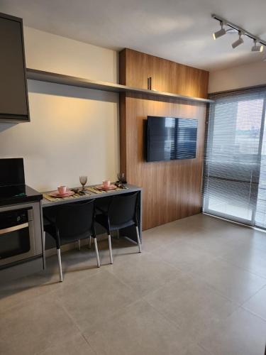 un soggiorno con tavolo, sedie e TV di Studio no centro com piscina a Juiz de Fora