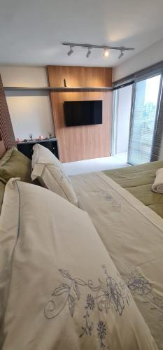 un grande letto in una stanza con televisore di Studio no centro com piscina a Juiz de Fora