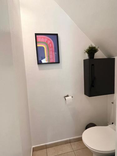 une salle de bain avec toilettes et un tableau au mur dans l'établissement #2 Charmante maison à 4 min Métro 9, à Bagnolet
