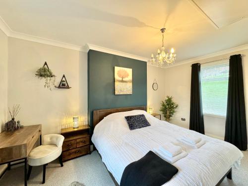 a bedroom with a bed and a desk and a chair at Chestnut Cottage in Dalmellington