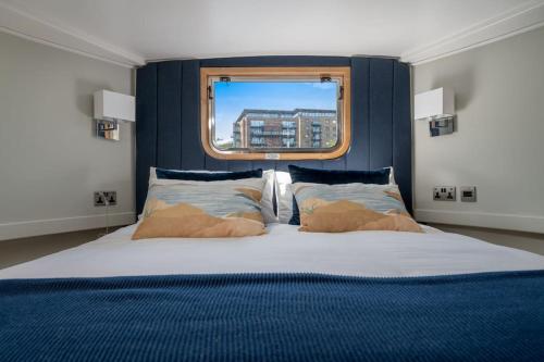 um quarto com uma cama grande e uma janela em Luxurious houseboat near Canary Wharf in London em Londres