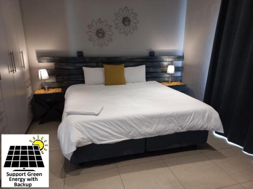 - une chambre avec un lit doté de draps blancs et d'oreillers jaunes dans l'établissement SnL Guesthouse at Visarend, à Malelane