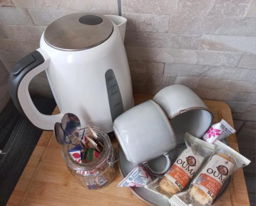 a tea kettle on a wooden table with food at SnL Guesthouse at Visarend in Malelane