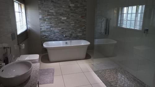 La salle de bains est pourvue d'une baignoire, de toilettes et d'un lavabo. dans l'établissement SnL Guesthouse at Visarend, à Malelane
