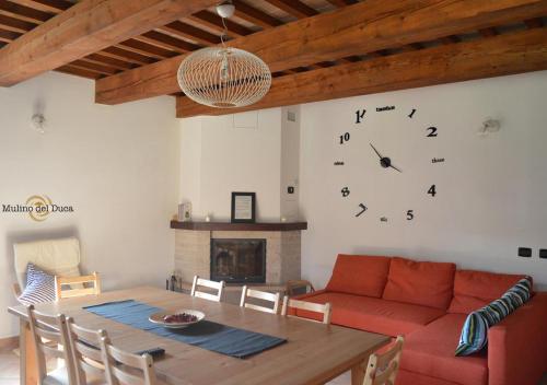 a living room with a red couch and a clock on the wall at Agriturismo Mulino del Duca in Urbino