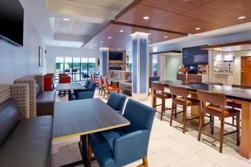 um restaurante com mesas e cadeiras e um bar em Holiday Inn Express Hotel & Suites Rochester Webster, an IHG Hotel em Webster