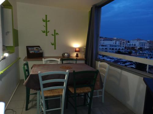 ein Esszimmer mit einem Tisch, Stühlen und einem Fenster in der Unterkunft MER, BATEAUX, Canaux in Sète
