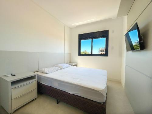 a small bedroom with a bed and a window at Apto NOVO, com piscina, 250m da praia in Bombinhas