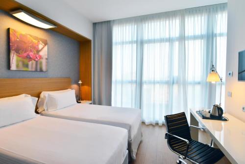 a hotel room with two beds and a desk at Hilton Garden Inn Milan North in Milan