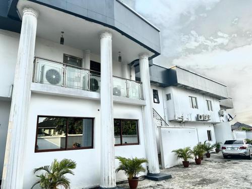 un bâtiment blanc avec colonnes et plantes en pot dans l'établissement Osmosis Ikoyi, à Lagos