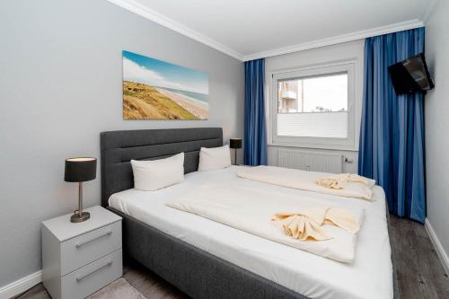 a bedroom with a large white bed with blue curtains at Sonnenidyll in Westerland