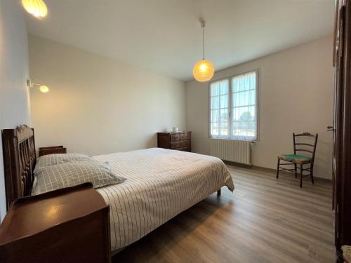 una camera da letto con un letto, una sedia e una finestra di Maison puyoo a Thèze