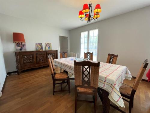 une salle à manger avec une table, des chaises et un lustre dans l'établissement Maison puyoo, à Thèze