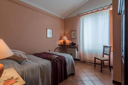 ein Schlafzimmer mit einem Bett und einem Stuhl und einem Fenster in der Unterkunft Casale Nocciolo in Bevagna